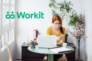 A woman sitting at a laptop works on her phone. addiction startup seed funding