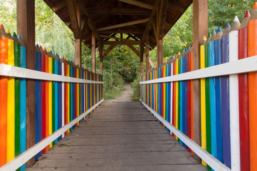 A covered bridge, with railings shaped and painted to look like rows of colored pencils