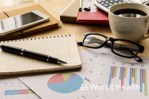 A cluttered desk with pie charts and work items.