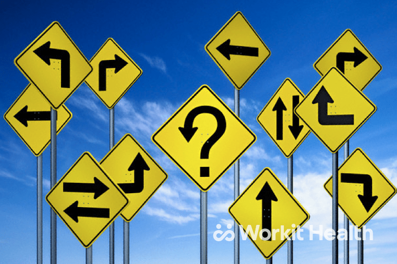 A collection of yellow traffic signs, all with arrows pointing in different directions, in front of a blue sky