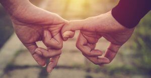 Closeup of holding hands by linking pinkies together.