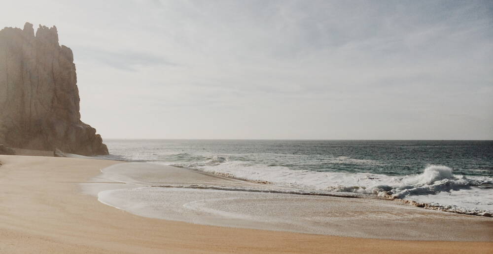 Peaceful, low contrast photo of an empty beach in Baja California, with waves breaking on the shore.