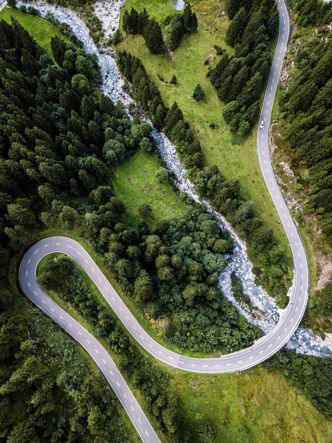 Aerial view of a road with a sharp, hairpin turn, winding across green landscape