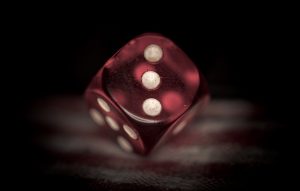 A red plastic die, showing three pips