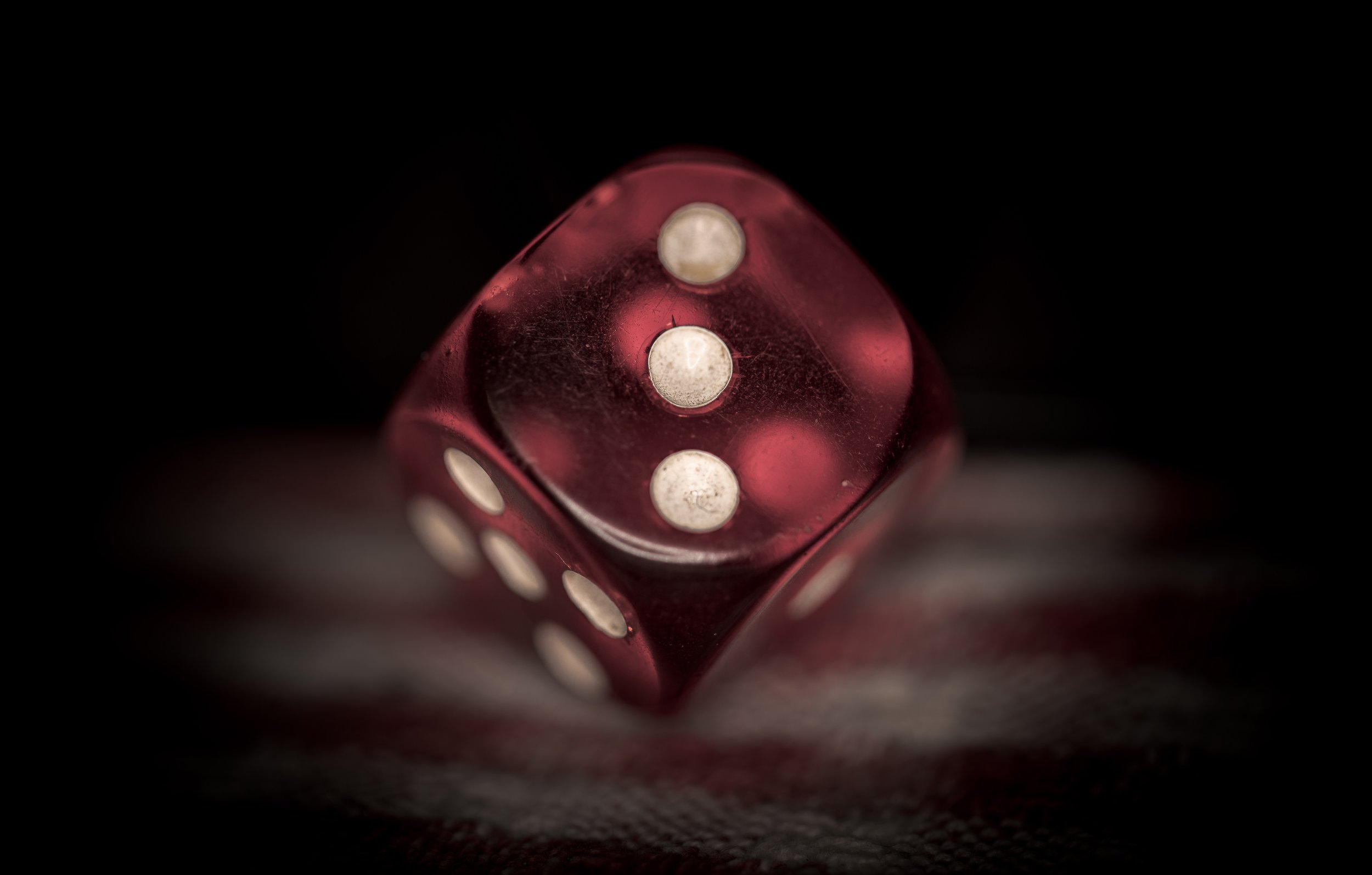 A red plastic die, showing three pips