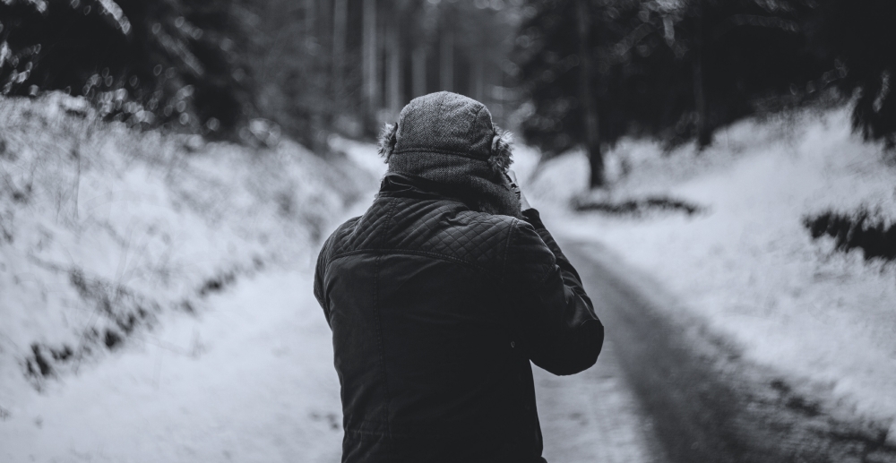 Walking alone on a snowy street, bundled up in coat and hat. Alone on Christmas? How to cope.