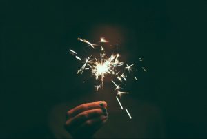 A hand holds a lit sparkler in the dark