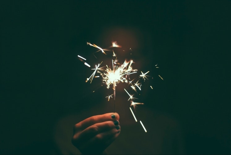 A hand holds a lit sparkler in the dark