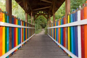 A covered bridge whose railings are shaped like colored pencils in rainbow colors.