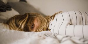 Woman lying face-down on a bed. Seasonal Affective Disorder in recovery