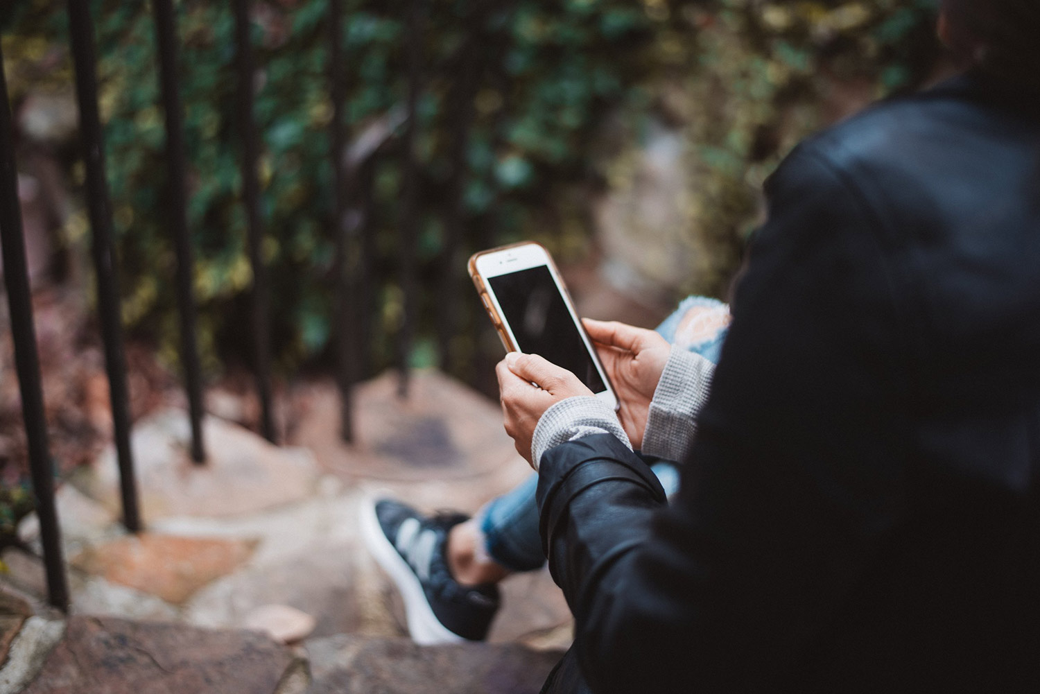 Sitting outdoors, looking at a phone. Priority Health