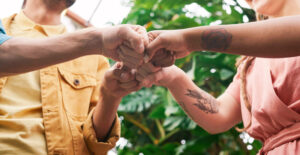 Close-up on the hands of four people doing a multi-person fist bump