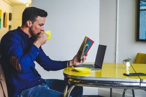 A man reads a book while drinking coffee