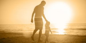 Father and small child walking on the beach