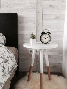 An old fashioned alarm clock on a bedside table beside a potted succulent