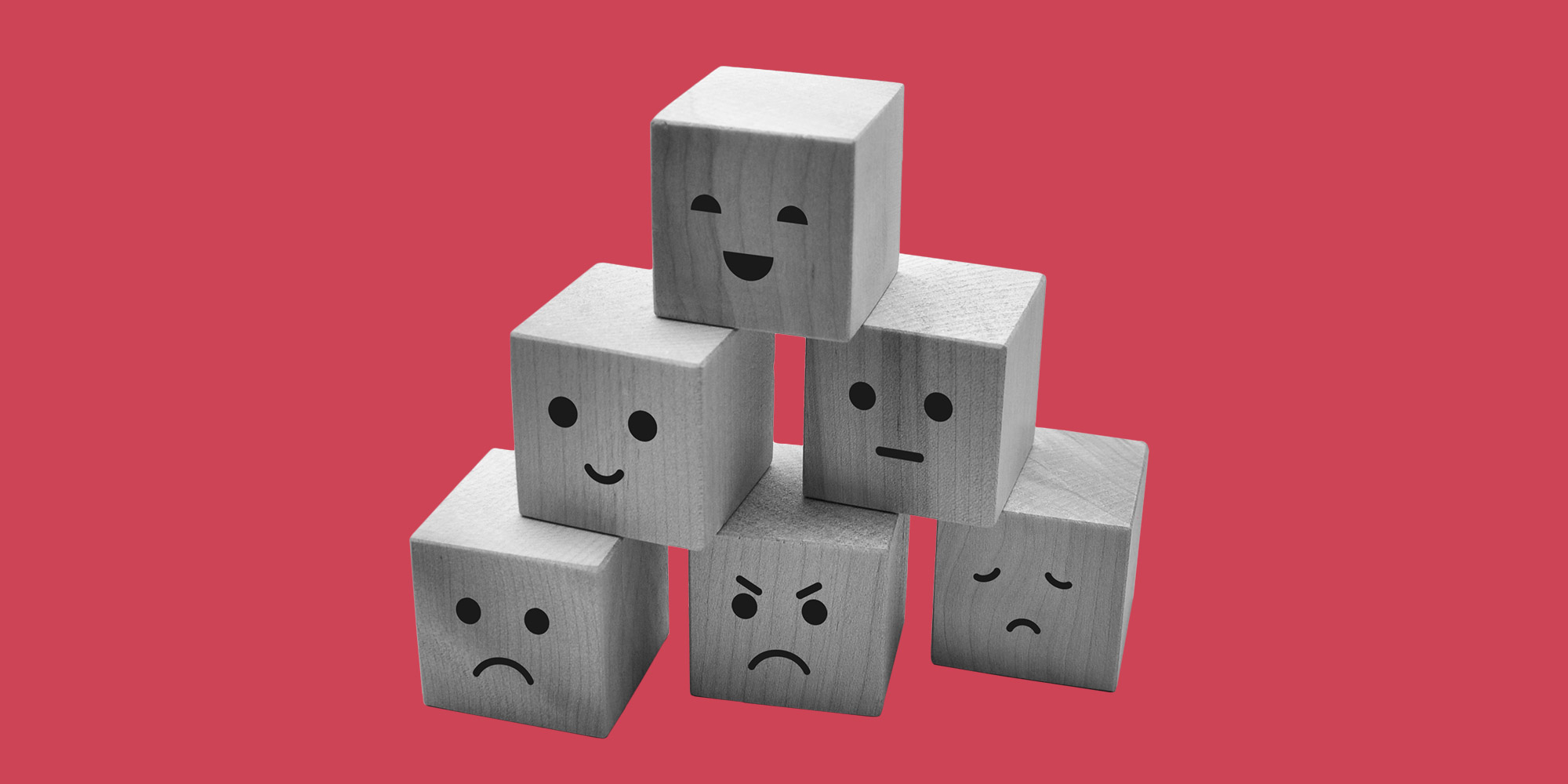 A stack of wooden children's blocks with facial expressions painted on them