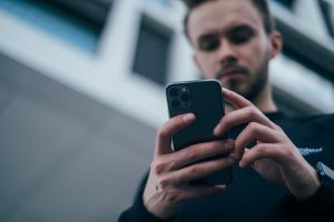 A man looking down at the phone in his hands. Medication assisted treatment