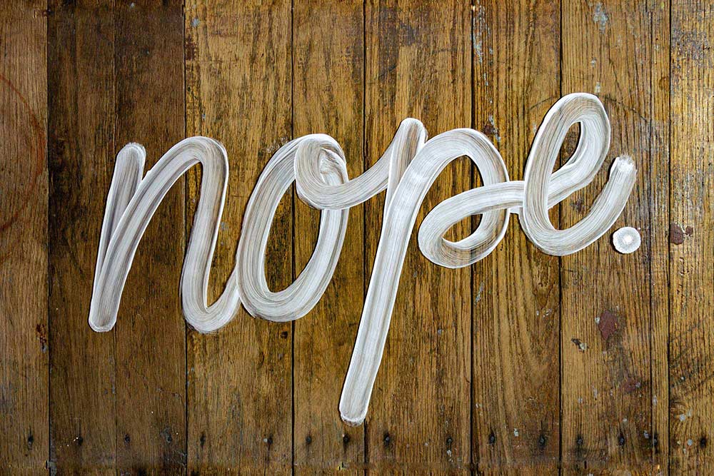 The cursive word "Nope." written in shaving cream on a wooden floor