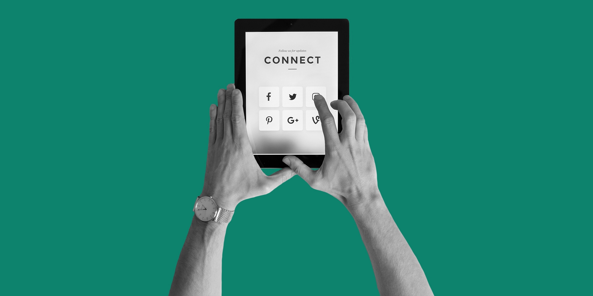 Grayscale photo of hands using a tablet to access social media, set against a dark green backdrop