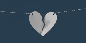 A torn paper heart strong on a horizontal string. Domestic Violence