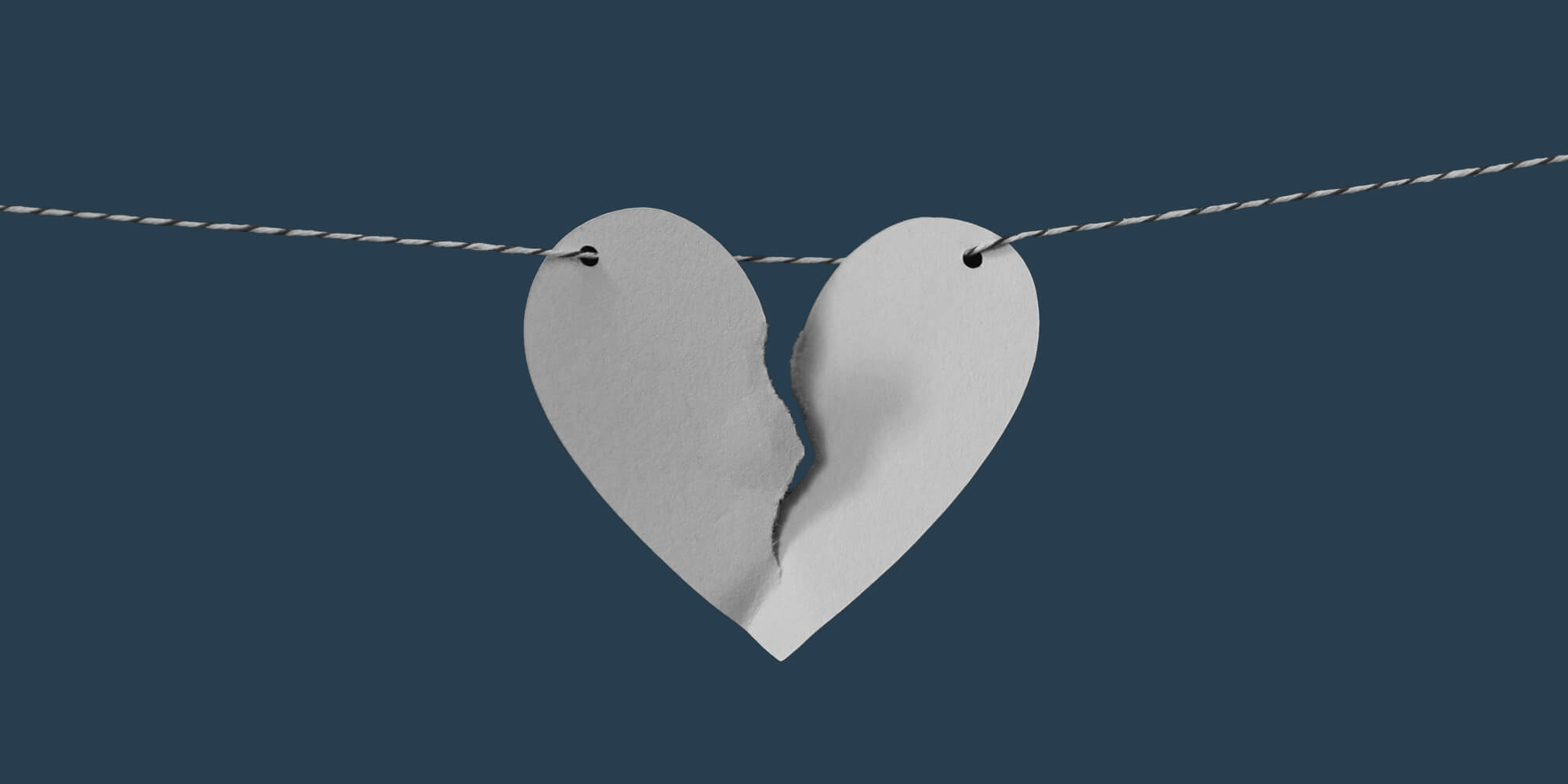 A torn paper heart strong on a horizontal string. Domestic Violence