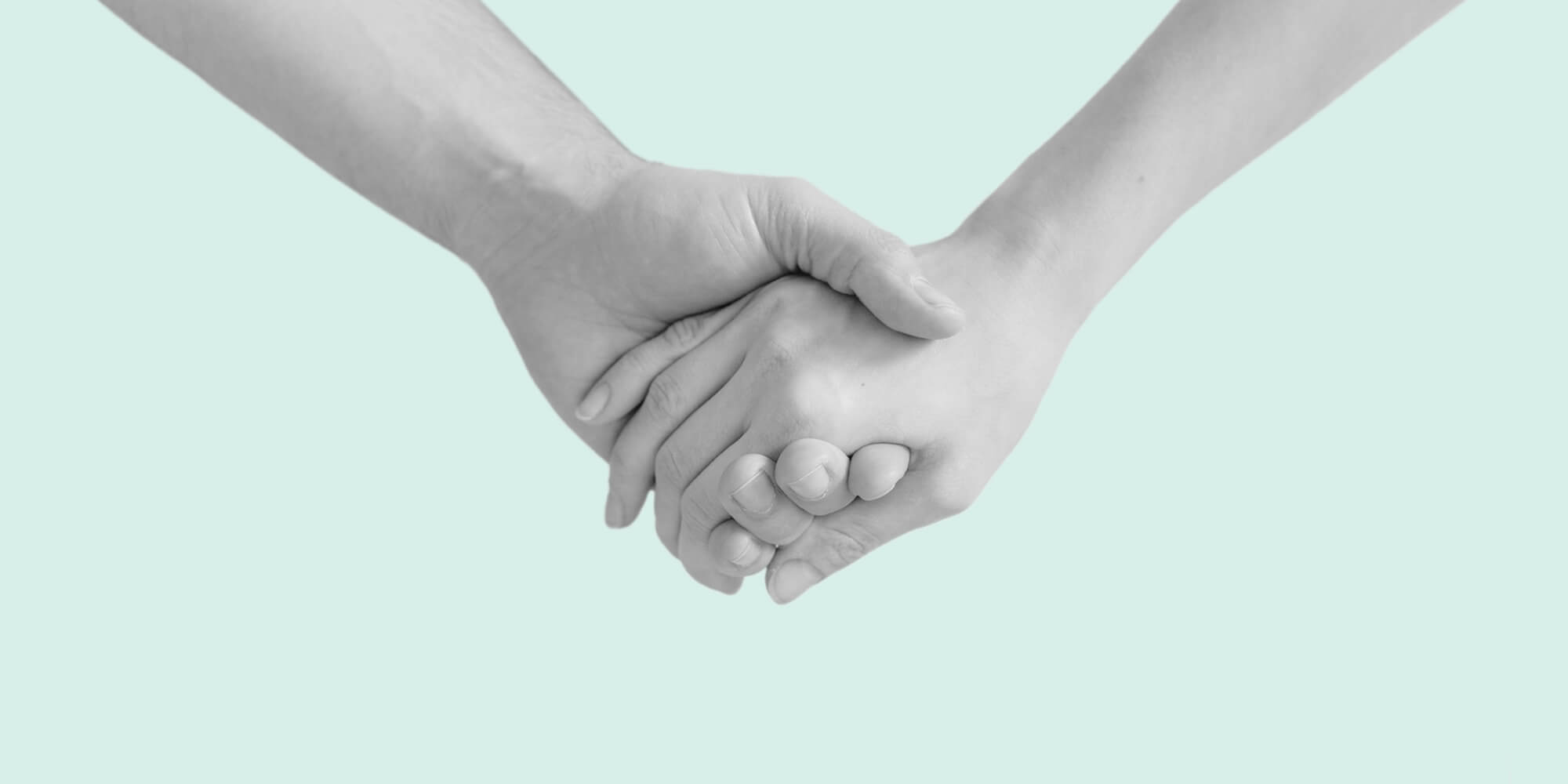 Holding hands against a pale green backdrop. True friendship in sobriety