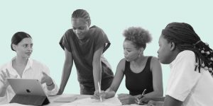 A group of four young Black women collaborating around a table. Mental health and recovery resources for BIPOC