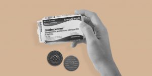 Hand holding a packet of Suboxone, with two sobriety chips in the background. Can Suboxone and the 12 steps work together?