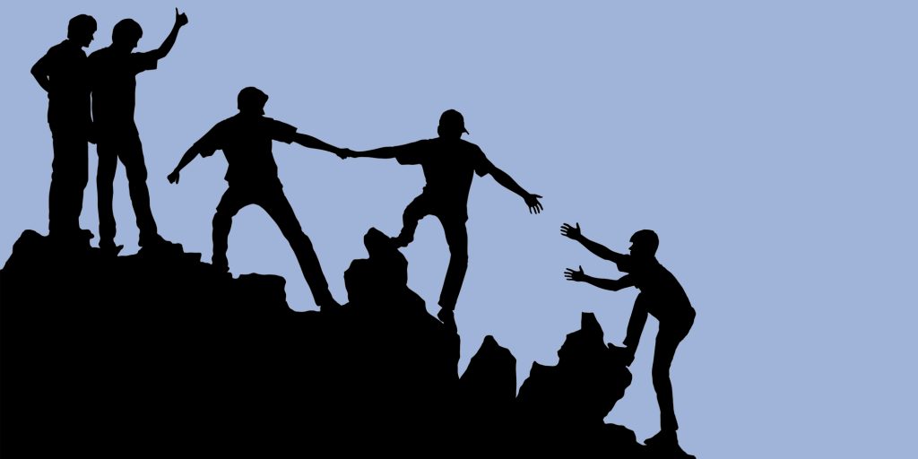 Silhouette of a group helping one another climb a rocky outcrop. Harm reduction