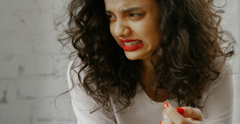 A woman with curly, dark hear grimaces in distaste.