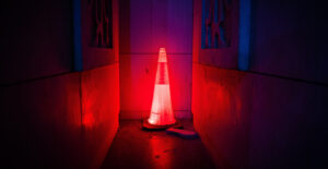 Glowing red safety cone in a dark, dingy corridor.