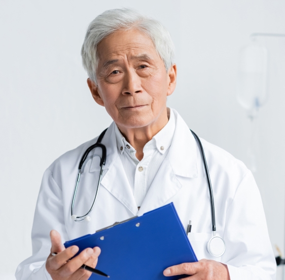 An older doctor holding a blue clip board