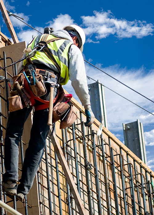 A constuction worker in a hard hat on a scaffold of rebar