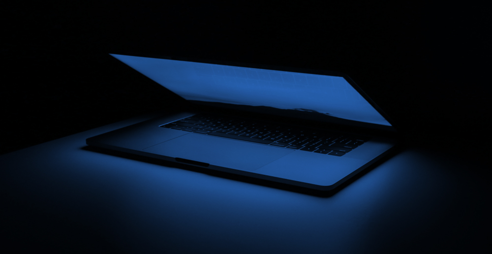 A glowing laptop on a dark background. Concerns about tech addition