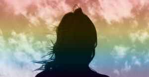 Silhouette of a woman's head against a sky that has a rainbow overlay. Coming out and coming clean.
