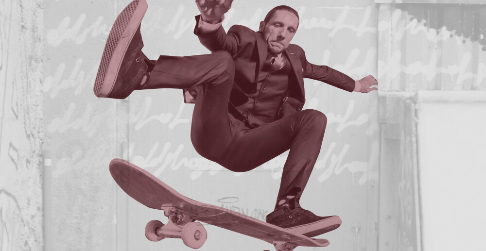 Brandon Novak performing a skateboard trick in a three-piece suit. Brandon's Novak: Rising from Rock Bottom