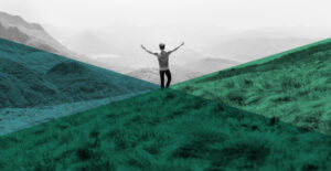 View from behind of a person standing on a hill, raising their arms in celebration. A journey to joy in recovery