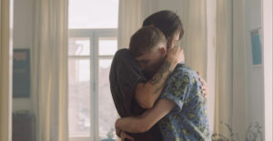 A couple embrace in a room full of windows