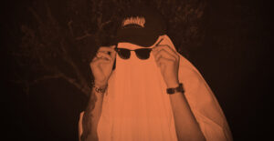A peron in a white sheet as a ghost costume, with a baseball cap and sunglasses on top. Spooky Sober Halloween Fun