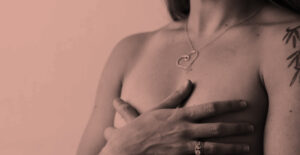 A topless woman covers her chest with her hands. Navigating cancer in early addiction recovery