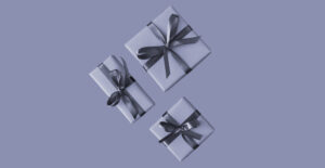Three wrapped gifts in monochrome on a blue-gray background. Holiday gift guide for people in addiction recovery.