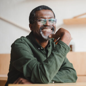 An African American man with glasses and a short gray beard smiles at the camera