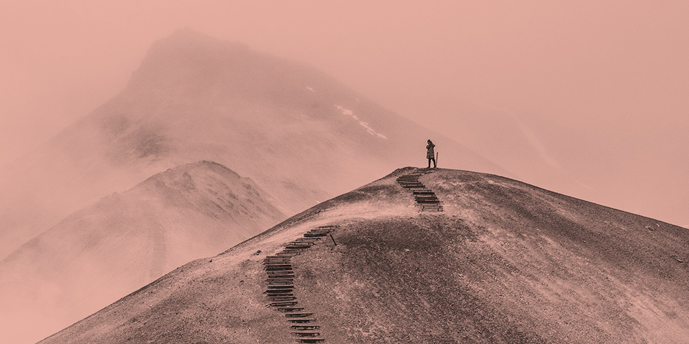 A person stands on a hilltop with stairs below them, cut into the side of the hill. Lessons learned at 10 years of recovery.