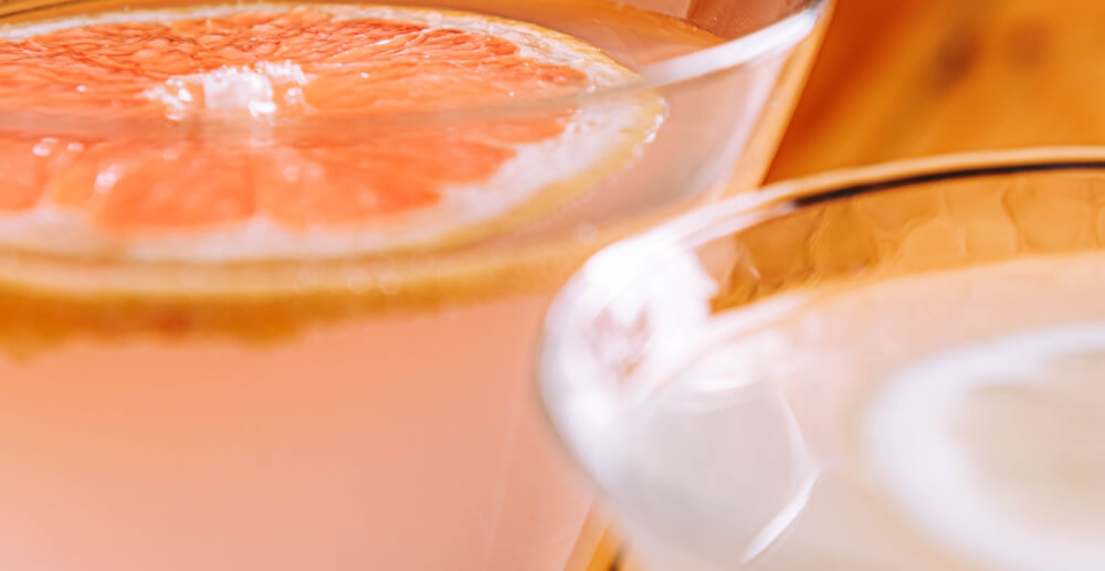 Close-up of mixes drinks in martini glasses, with slices of citrus floating on top. How to make a mocktail cheat sheet