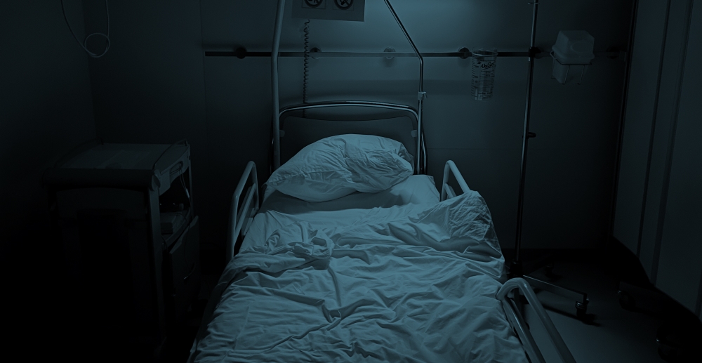 An empty hospital bed with rumpled sheets, with a dark blue color overlay on the photo. Staying sober through a parent's death.