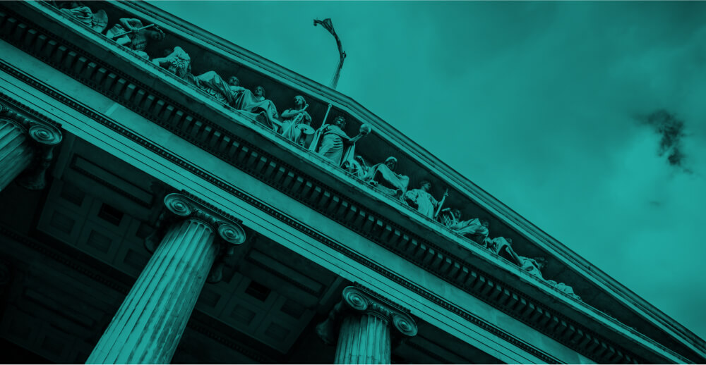 Green color overlay on a black and white photo looking up at a courthouse decorated with carved figures and pillars. Post-COVID regulations and telemedicine addiction care