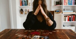 An upset brown-haired woman sits at a table that holds souvenirs of a relationship