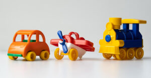 Brightly colored plastic toys: a car, an airplane, and a train. Traveling sober