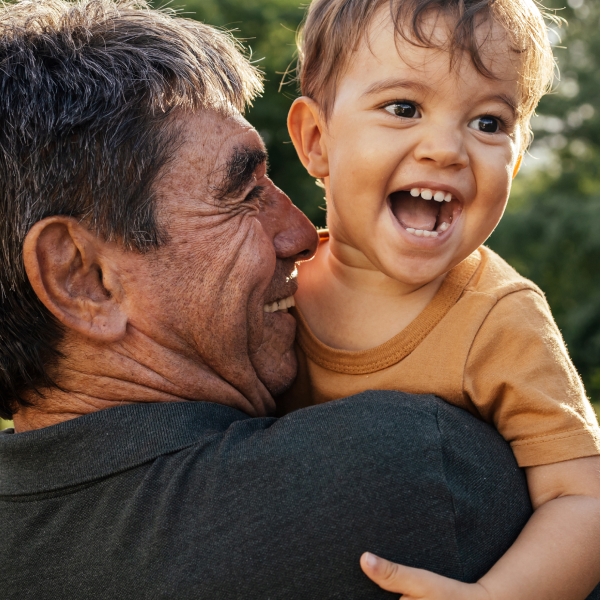 A middle-aged White man holds a small child on his shoulder. Both are grinning delightedly.