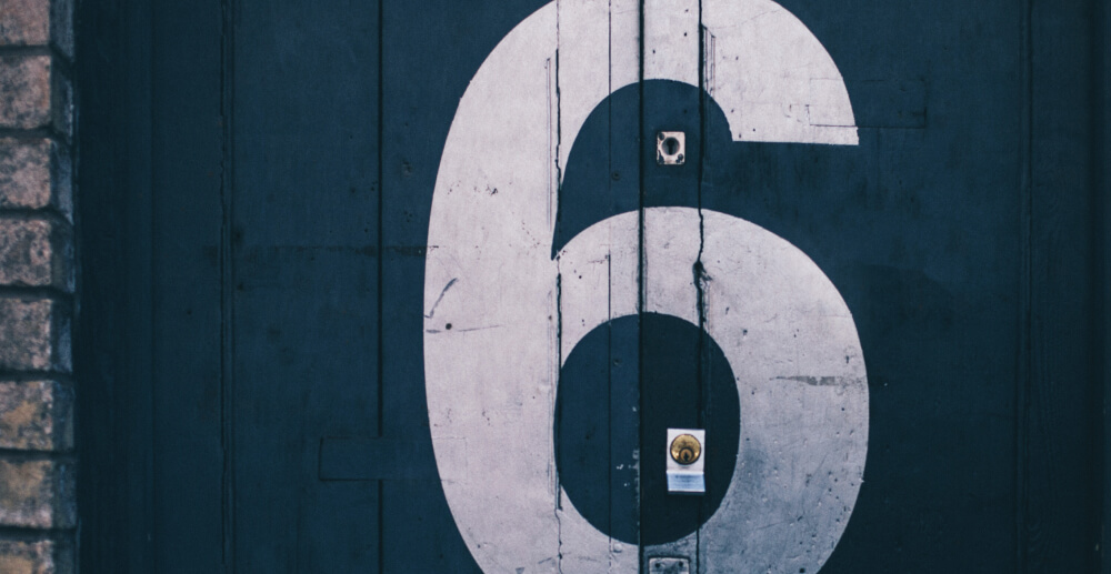 A large number 6 stenciled in white on a dark blue door